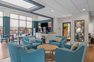 uma sala de espera com cadeiras azuis e uma mesa em Garnet Inn & Suites, Morehead City near Atlantic Beach em Morehead City
