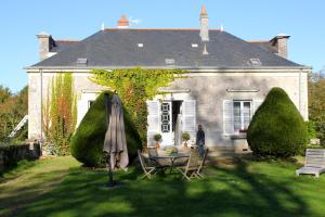 una casa con tavolo e ombrellone in cortile di Le Domaine Du Cormier a Orvault