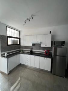 a kitchen with white cabinets and a stainless steel refrigerator at Coconoa Beach in Playa del Ingles