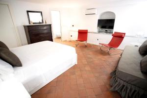 una camera con un letto bianco e due sedie rosse di Palazzo Marletta Duomo Apartment a Catania