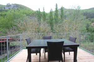 une table et des chaises noires sur une terrasse avec vue dans l'établissement Maison au bord de l'eau avec Jacuzzi, à Millau