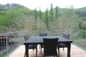 una mesa negra y sillas en una terraza con vistas en Maison au bord de l'eau avec Jacuzzi, en Millau