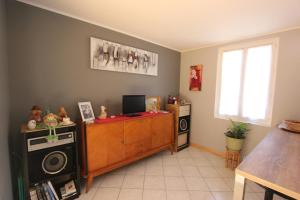 sala de estar con TV y escritorio con ordenador en Maison au bord de l'eau avec Jacuzzi, en Millau