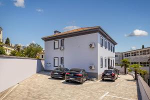 a white house with cars parked in a parking lot at Agostini Residence - SELF CHECK-IN ONLY in Rijeka