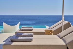 a row of chaise lounges on a yacht with the ocean at Ios Grand Pool Suites in Mylopotas