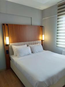 uma grande cama branca num quarto com duas luzes em KB Apart Otel em Talas