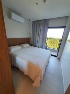 een slaapkamer met een wit bed en een groot raam bij Salinas Premium Resort 2/4 in Salinópolis
