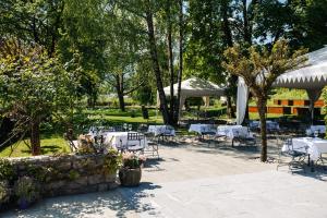 a patio with white tables and chairs and trees at Vila Podvin in Radovljica