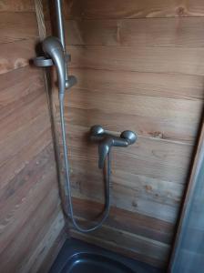 a metal shower in a room with a wooden wall at Apartma Kačwa in Kobarid