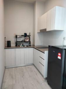 a kitchen with white cabinets and a black refrigerator at Lovely Seaview Condo TII @ Jesselton Quay in Kota Kinabalu