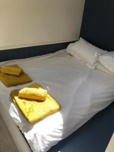 Una cama con sábanas blancas y toallas amarillas. en Lewes Beautiful sunny flat in the historic town, en Lewes