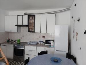 a kitchen with white cabinets and a table in it at Apartma Lavanda Istriana in Pobegi