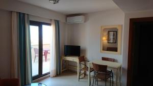 a room with a table and a television and a balcony at JARDINES DE ISLA CANELA By SIT ISLA CANELA -REF 171- in Isla Canela
