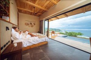 a man and woman laying in bed in a room with a view at LALOON Luxury Suites - Adults Only in Santa Teresa Beach