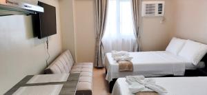 a small room with two beds and a television at Sunvida Tower Stays Across SM City Cebu in Cebu City