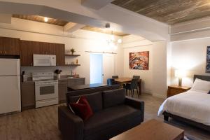 a living room with a bed a couch and a kitchen at Le Central in Rouyn-Noranda