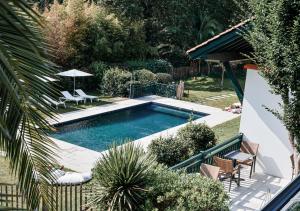 a swimming pool in a yard with two chairs and an umbrella at Les Frères Ibarboure - Hôtel 4 étoiles, Spa extérieur sensoriel et Restaurant étoilé à Bidart in Bidart