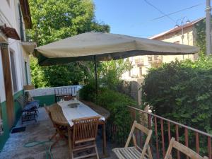 una mesa y sillas bajo una sombrilla en el balcón en Calabria Melia di Scilla collina Antico Casale con giardino bio naturale, en Castagnarella
