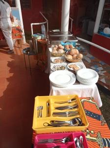 a table with plates and utensils and food on it at Residencial Brigada in Santo António