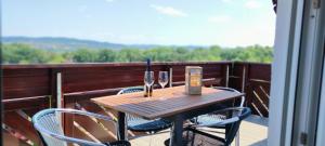 a wooden table with two wine glasses on a balcony at Ferienwohnung Rhöner WeitBlick in Burghaun