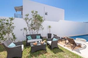 un patio con sillas, una mesa y una piscina en villa Pergola en Hammamet