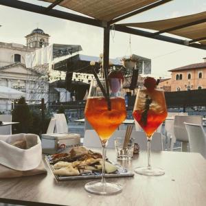 two drinks on a table with a plate of food at Piazza del Mercato in LʼAquila