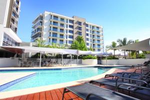 uma piscina com cadeiras e guarda-sóis ao lado de um edifício em Signature Waterfront Apartments em Gold Coast