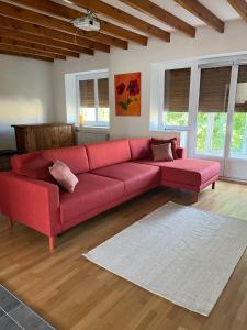 ein rotes Sofa im Wohnzimmer mit Fenstern in der Unterkunft Appartement dans maison avec cour et parc in Fresnes-en-Woëvre