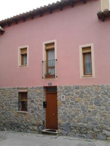 een roze huis met een deur en een stenen muur bij La Ontina in La Puebla de Valverde