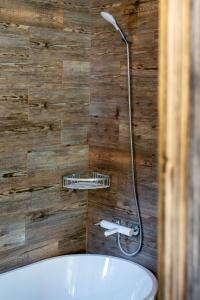 een badkamer met een houten wand, een douche en een bad bij Vila Mesteacanul in Moieciu de Sus