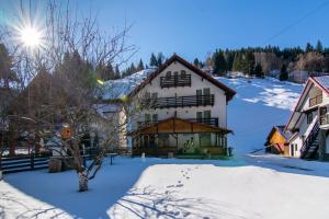 a house in the snow with snow covered ground at Vila Mesteacanul in Moieciu de Sus