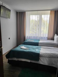 dwa łóżka w pokoju z oknem w obiekcie Selment Resort w mieście Ełk