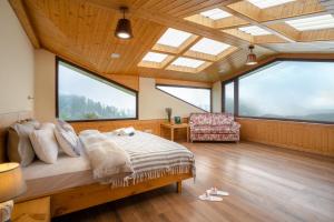 a bedroom with a bed in a room with large windows at Hostie Mystica-Highest Penthouse with Terrace, Mashobra in Shimla