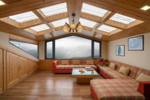 a living room with couches and a ceiling with windows at Hostie Mystica-Highest Penthouse with Terrace, Mashobra in Shimla