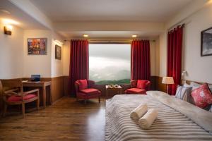 a hotel room with a bed and a desk and a window at Hostie Mystica-Highest Penthouse with Terrace, Mashobra in Shimla