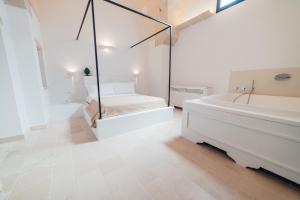 a white bathroom with a tub and a bed and a bath tub at Tenuta Tresca Suites - Dimora Storica in San Cassiano