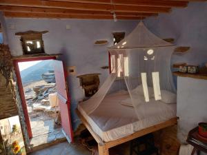 a bedroom with a bed with a mosquito net at Katerina's Sunset in Panormos