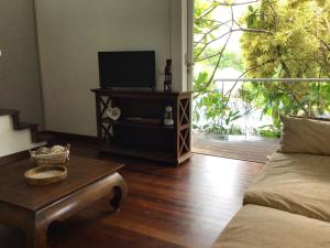 Sala de estar con sofá y mesa con TV en Le Cottage, en Sainte-Rose