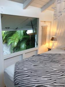 a bedroom with a large window with a bed at Le Cottage in Sainte-Rose +36 photos