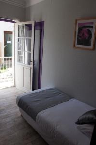 1 dormitorio con 1 cama y puerta abierta en Le Pavillon Bleu Hotel Restaurant en Royan
