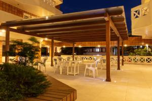 een patio met witte stoelen en tafels in een gebouw bij Ilhasul Hotel Residencia in Florianópolis