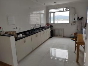 uma cozinha com armários brancos e uma grande janela em Vista ao Mar em Santos