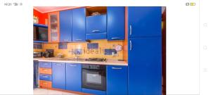La cuisine est équipée de placards bleus et d'un four avec plaques de cuisson. dans l'établissement Le Note del Mare appartamento vista mare, à Roccalumera