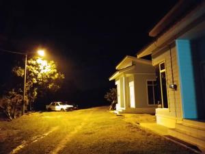 a car parked next to a house at night at Teratak Sherra Roomstay in Machang