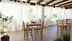 a dining room with white curtains and a table and chairs at Villa Mameli b&b in Rena Majore +33 photos