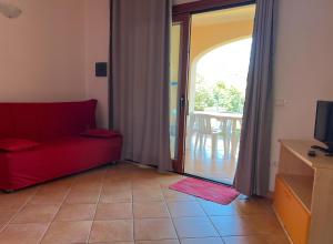sala de estar con sofá rojo y balcón en Casa Vacanze Terrapadedda 1, en San Teodoro