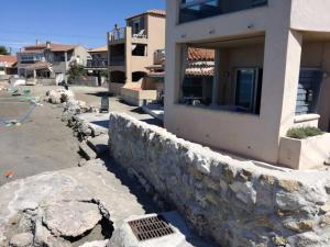 a stone retaining wall next to a building at La Maison de la Mer - 1er Étage in Fos-sur-Mer