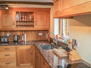 a kitchen with wooden cabinets and a sink at Medieval Cottage in rural Monmouthshire. in Raglan