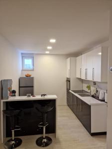 a kitchen with white cabinets and a black island with bar stools at Wellness apartment BLACK-WHITE in Široki Brijeg