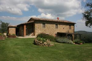 a small stone house with a grassy yard at Podere della Crocchia in Ciggiano